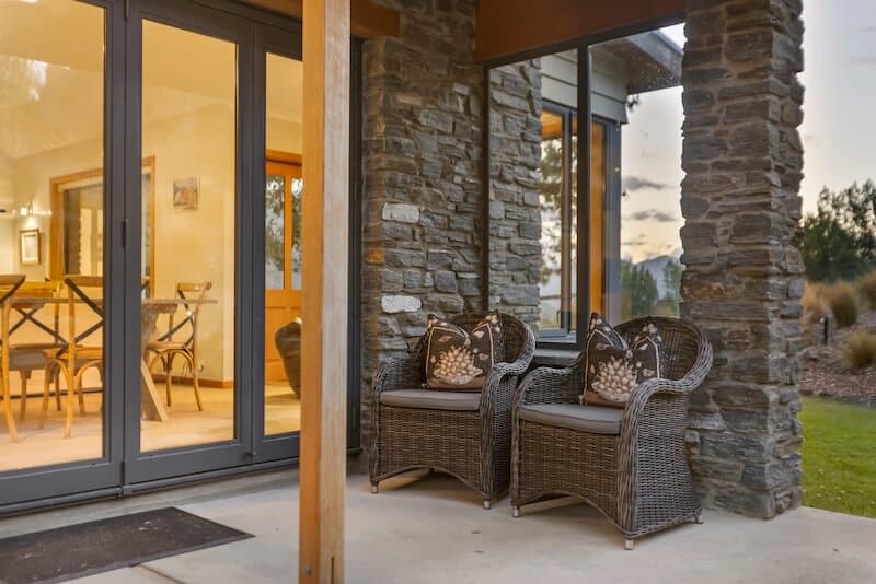 Cozy outdoor seating area with wicker chairs and decorative pillows at Judge & Jury Village, perfect for relaxing and enjoying the scenic surroundings of the village.