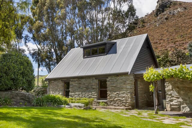 1. Stone cottage at Judge & Jury Village in New Zealand, surrounded by greenery and scenic landscapes, perfect for unique accommodations in North Island.